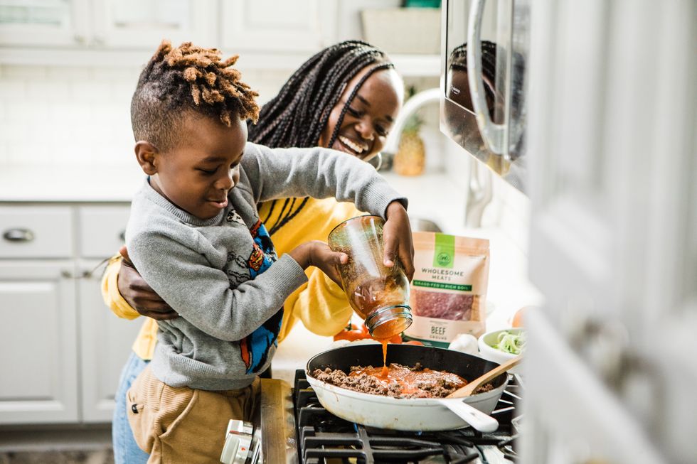 boy in gray long sleeve shirt pouring sauce in pan