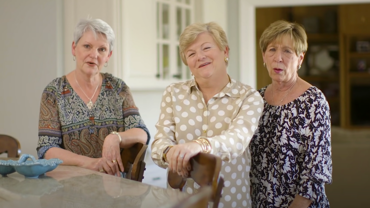 Three grandmas stand in a kitchen.