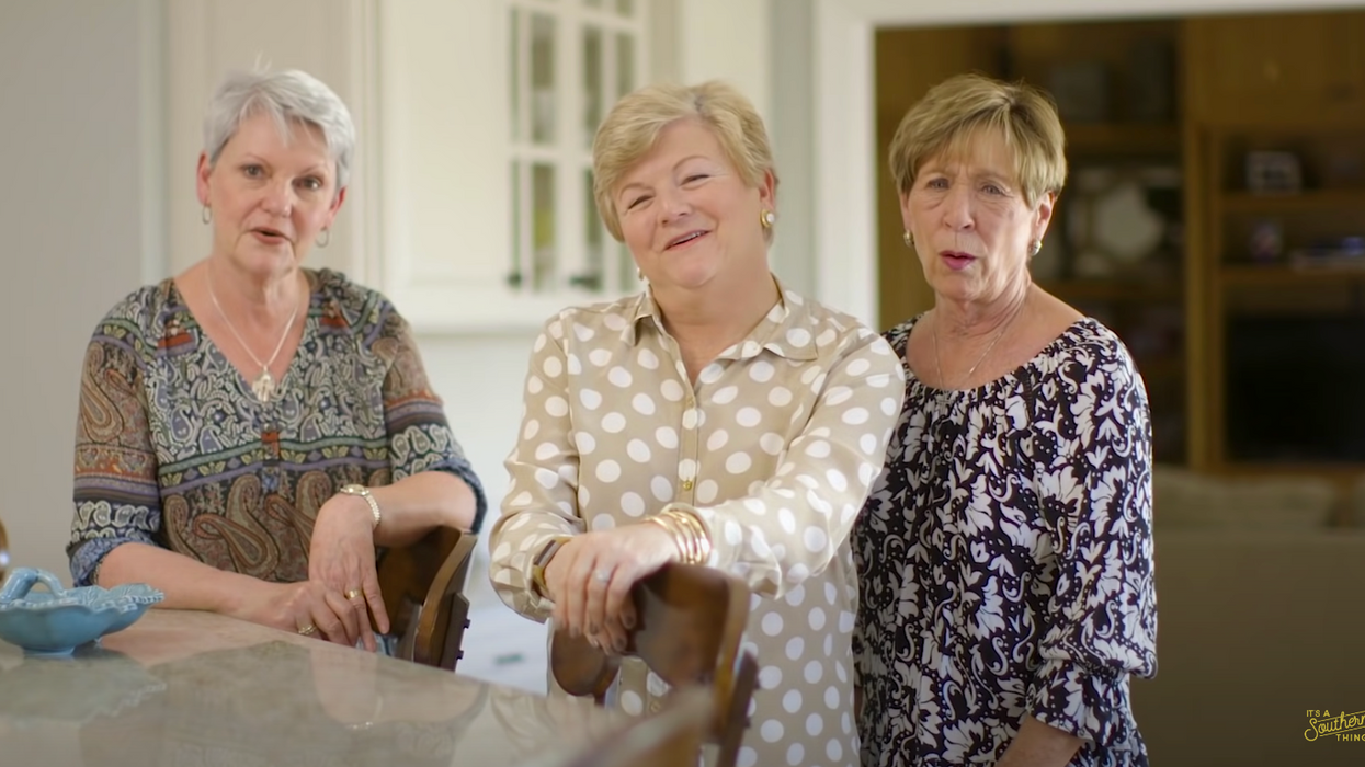 Three grandmas stand in a kitchen.