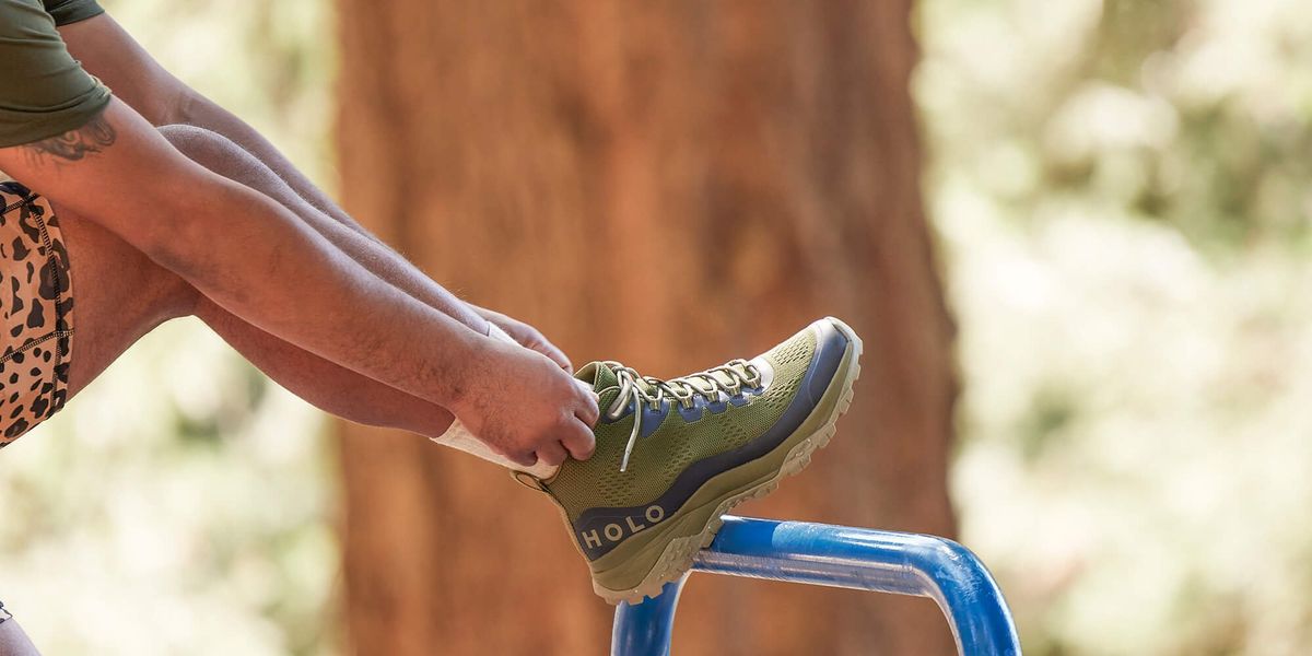 man bends over with his foot up on a bar so he can tie his shoes