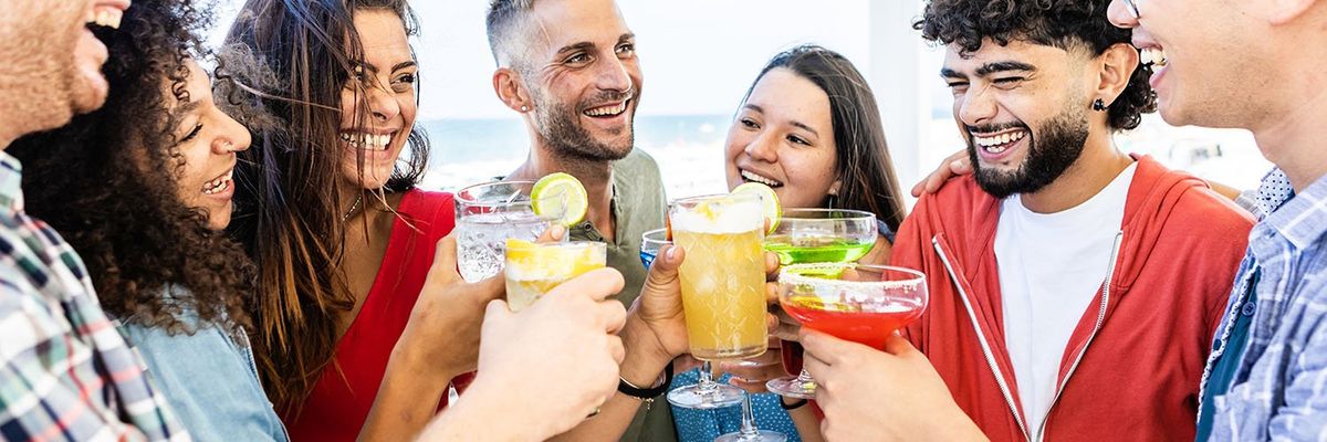 a group of friends clinking cocktail glasses and smiling