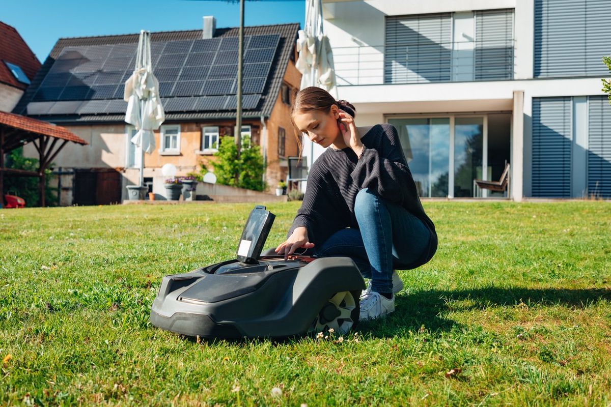 a photo of a woman setting up a robot mower