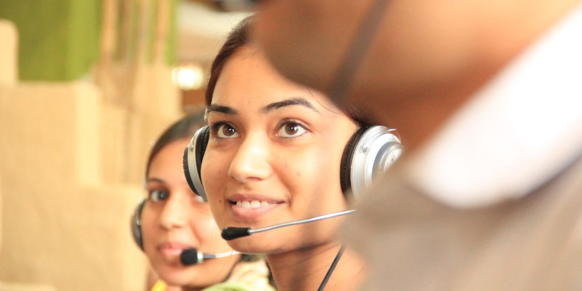 Two customer service workers with headsets look up