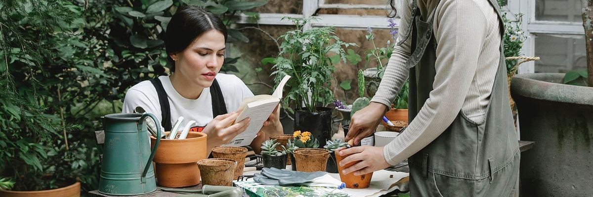 a photo of two women planting on clay pots