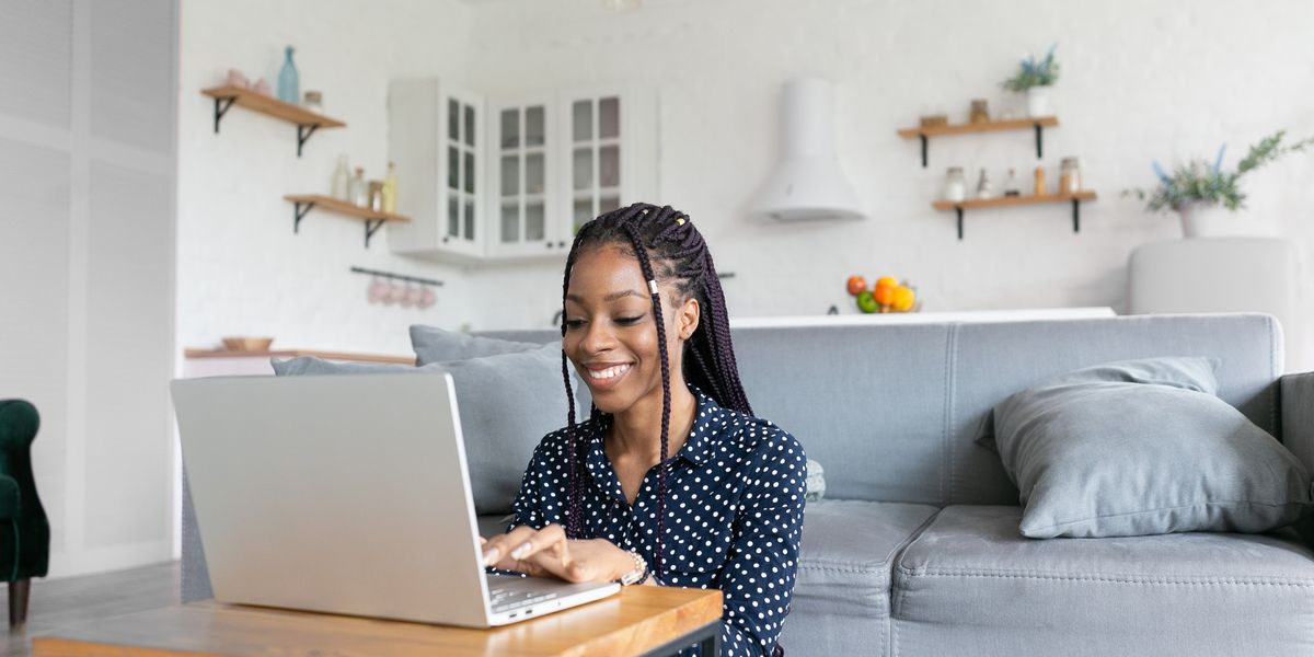 Black-woman-sitting-on-floor-while-working-remote-job-zoom-call