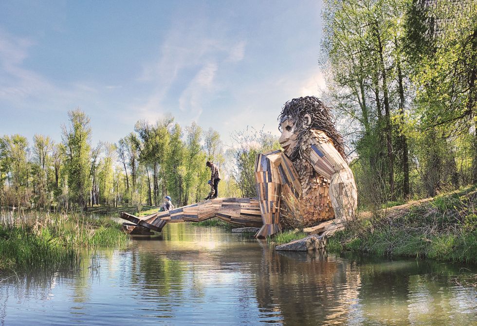 Troll sculpture with leg extending over a river