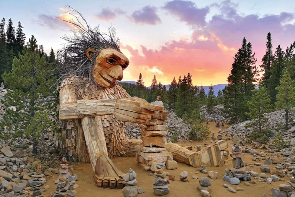 Giant wooden troll sitting on the ground building rock towers