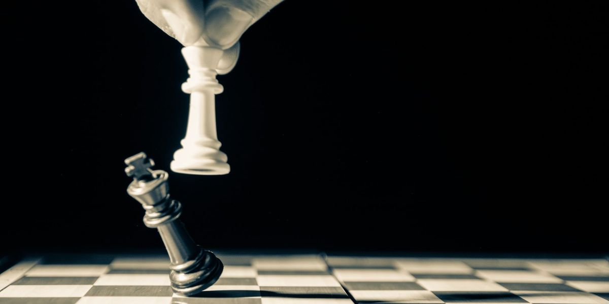 On a black and white chessboard a White King topples a Black King
