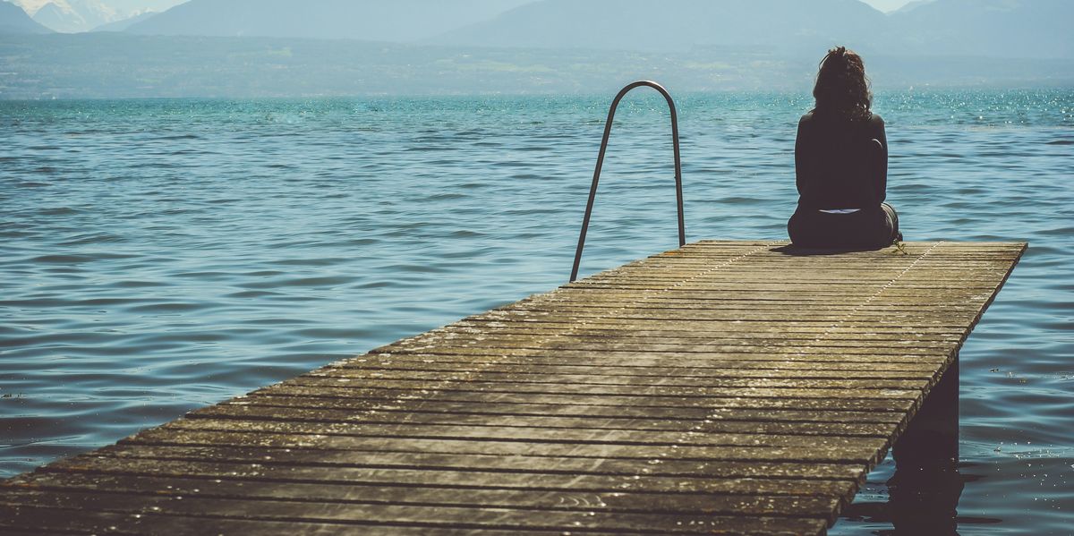 Woman sitting alone at the edge of a dock