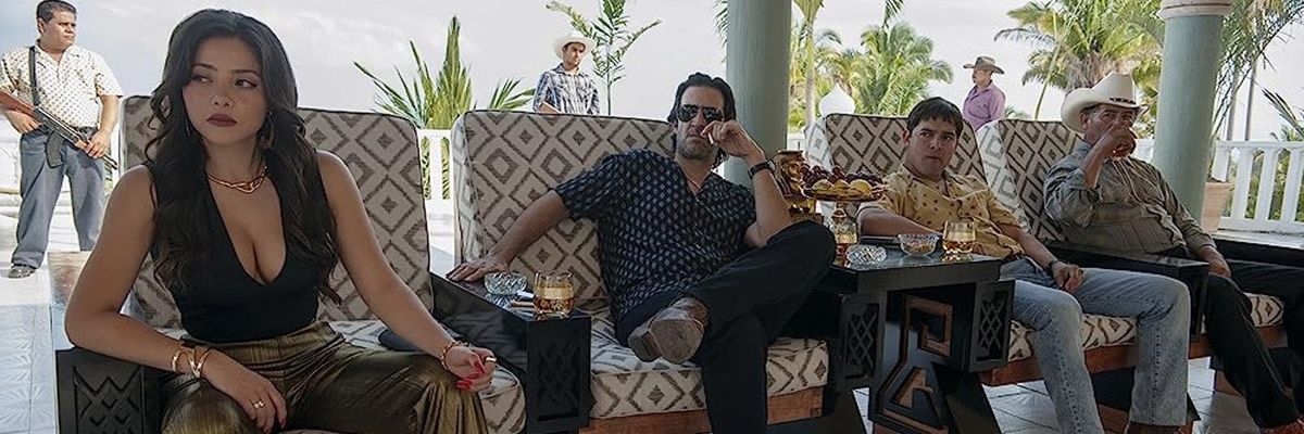 A still image from the Netflix series "Narcos Mexico" depicting a woman and three men sitting inside a luxury home.