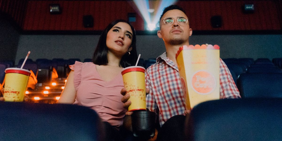 Couple in movie theater with drinks and popcorn