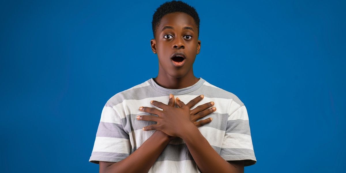 A young man stands in shock with his hands folded over his chest