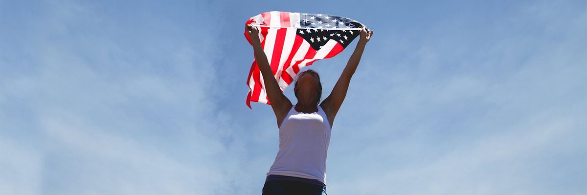 a woman holding a USA flag with the blue sky as a background