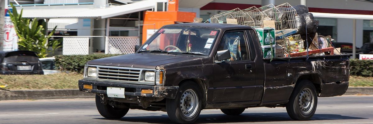 an old, scraped pick up truck with a lot of junk in the bed