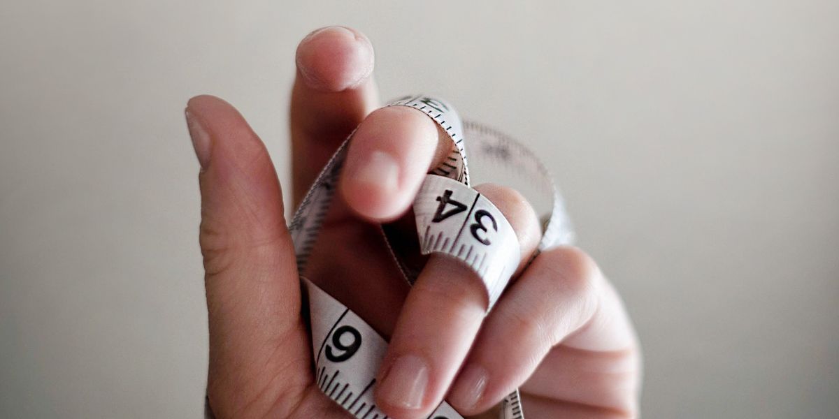 person's left hand wrapped by tape measure