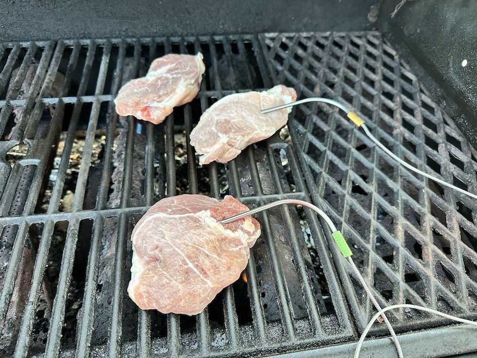 a photo of pork chops on a grill with meat probes in them