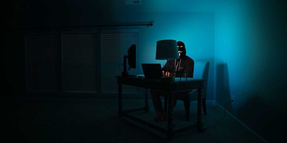 Suspicious person using computers in darkened room