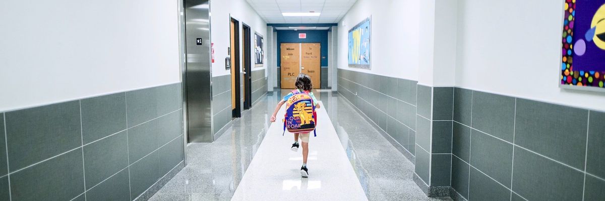 a photograph of a kid with a backpack running through a school hall