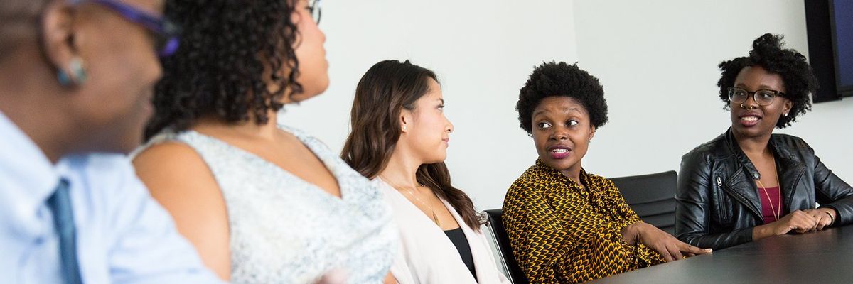 a diverse group of people speaking at a work meeting
