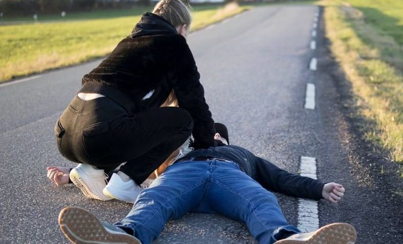 Someone tending to a man collapsed on a roadway