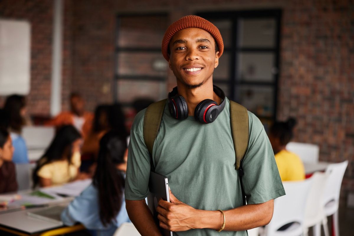 A photo of a college student wearing headphones and carrying a laptop 