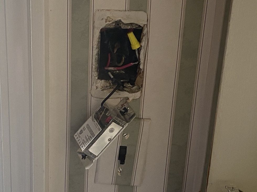 a photo of a smart switch being removed from an outlet with only two wires