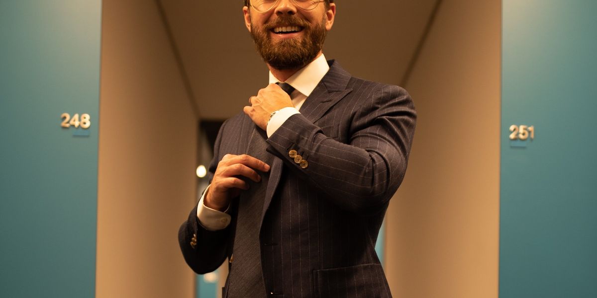 person in pinstriped suit jacket straightening their tie