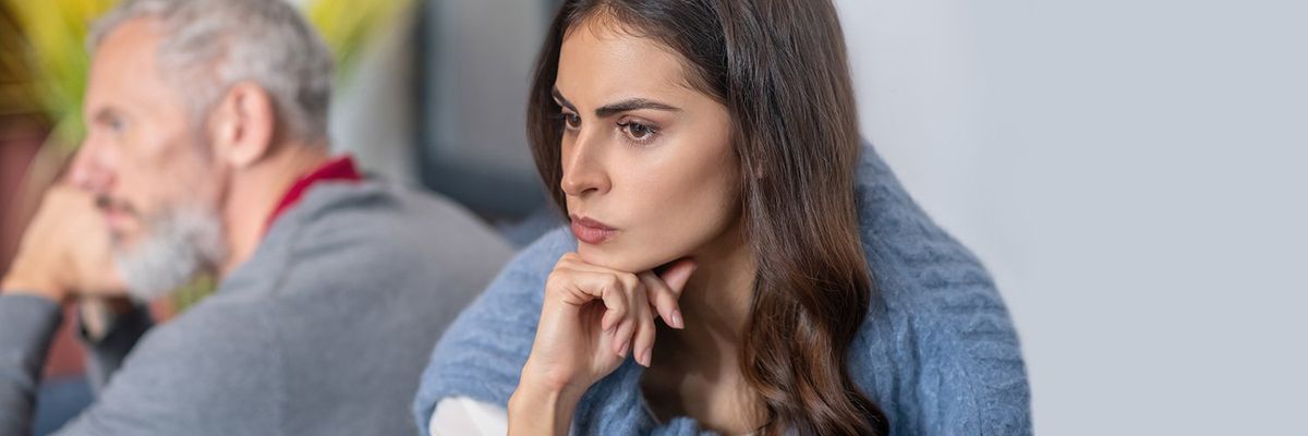 an image of a contemplative woman with an older man in the back