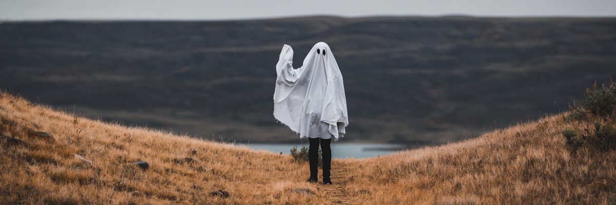 an image of a person covered in a white sheet with two holes for eyes like a ghost
