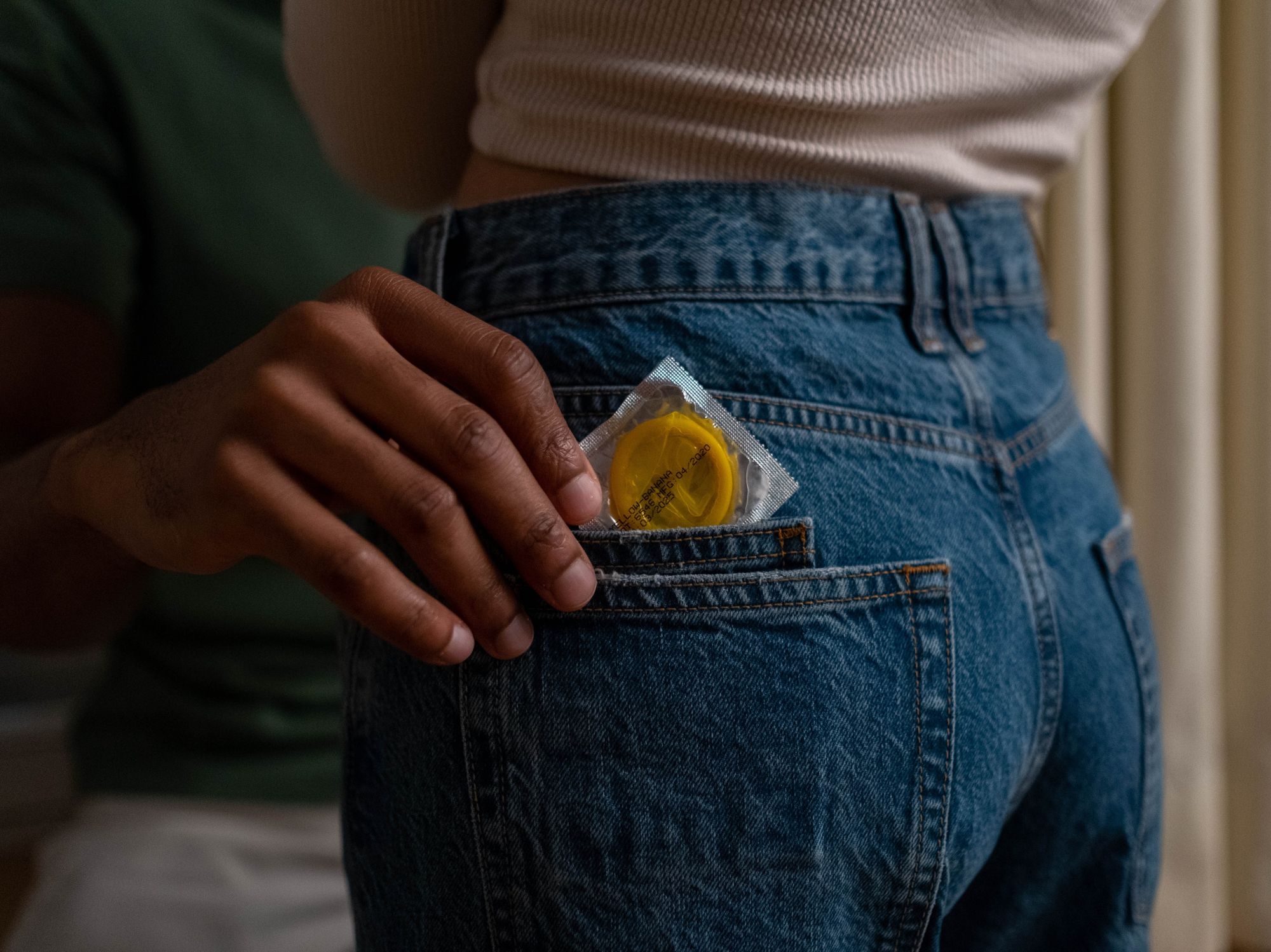 image of a person putting a condom in the back pocket of another person's jeans