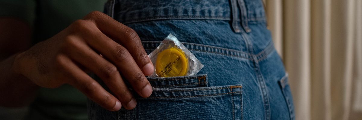image of a person putting a condom in the back pocket of another person's jeans
