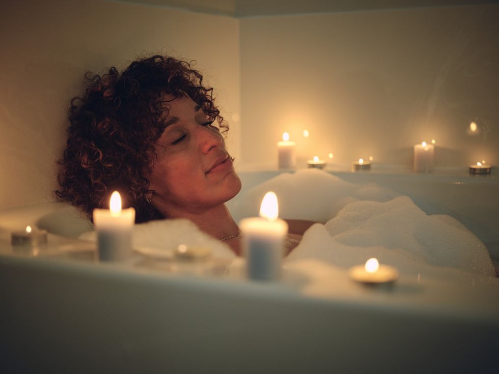 Woman-resting-in-a-bubble-bath-near-candle-light
