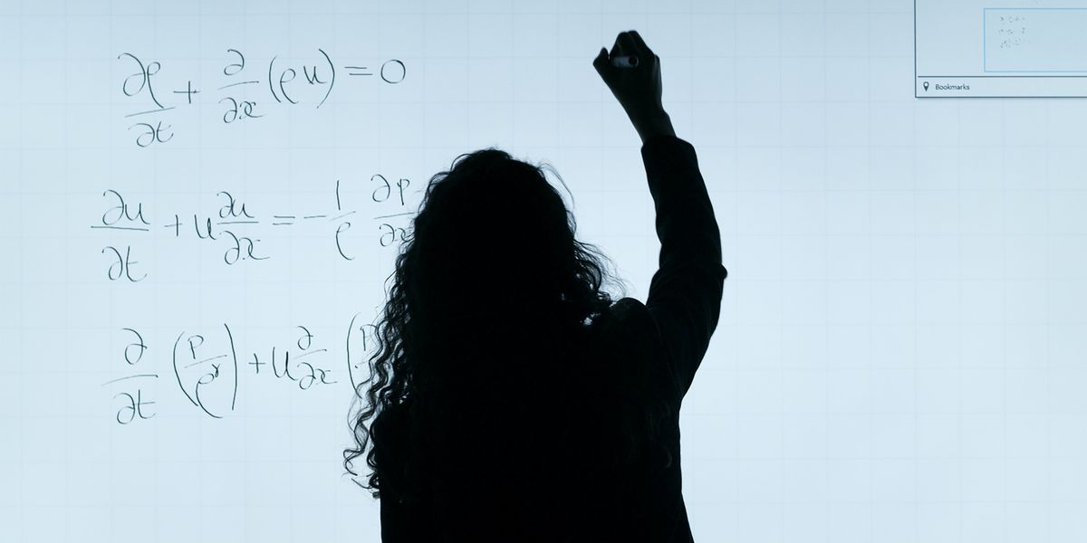 Person writing a complicated formula on a white board