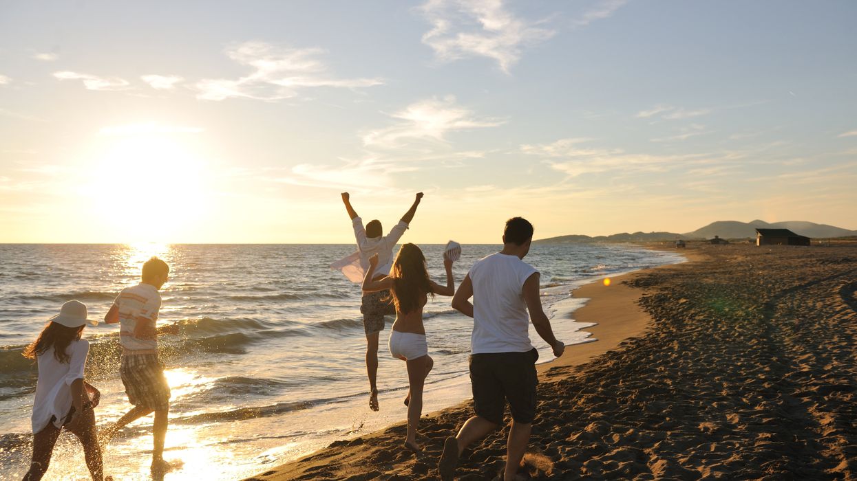 5 people run on a beach at sunset.