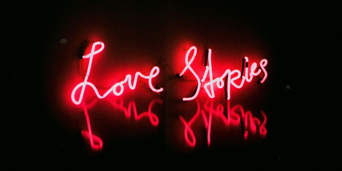 A red neon sign that says Love Stories and it's reflection