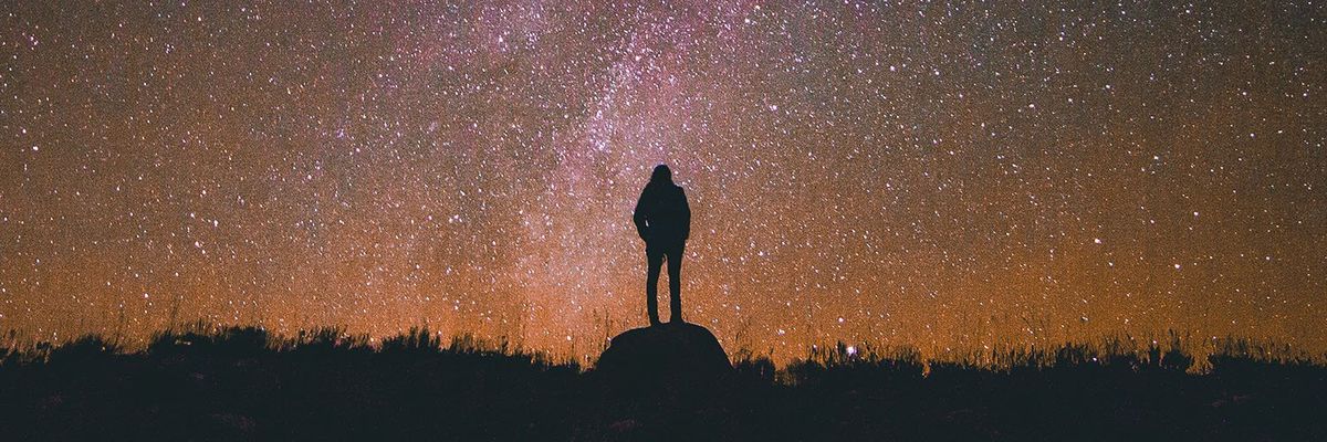 an image of a woman standing on top of a rock and looking up at the starry night sky