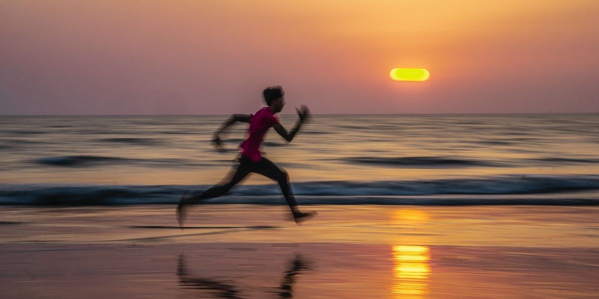 A person runs on a beach at sunset