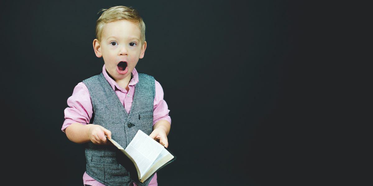 Shocked little boy wearing dress clothes and holding a book