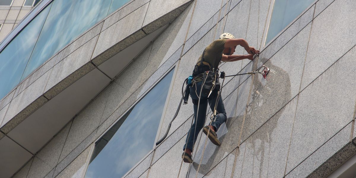Maintenance worker dangling on the side of a skyscraper