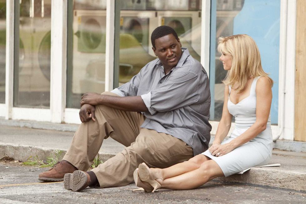 Black man and white woman sitting on sidewalk