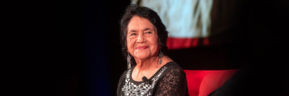 Dolores Huerta smiling sitting on a red couch