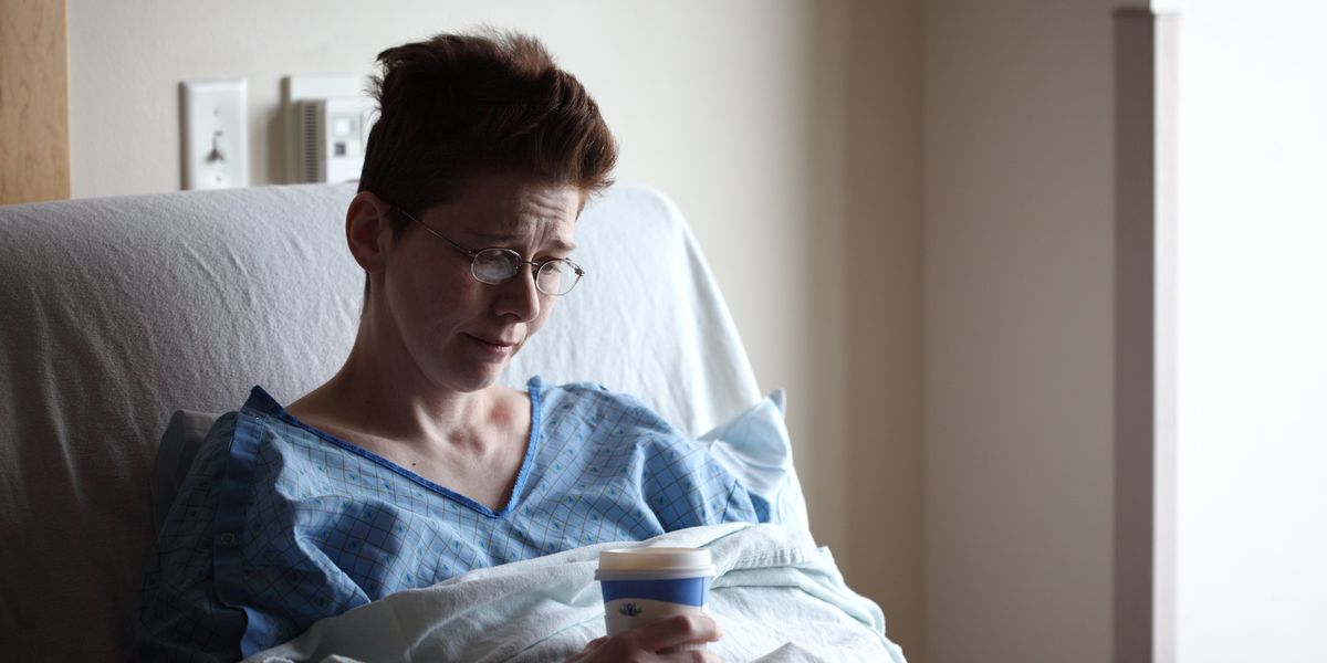Upset woman in hospital bed with coffee cup