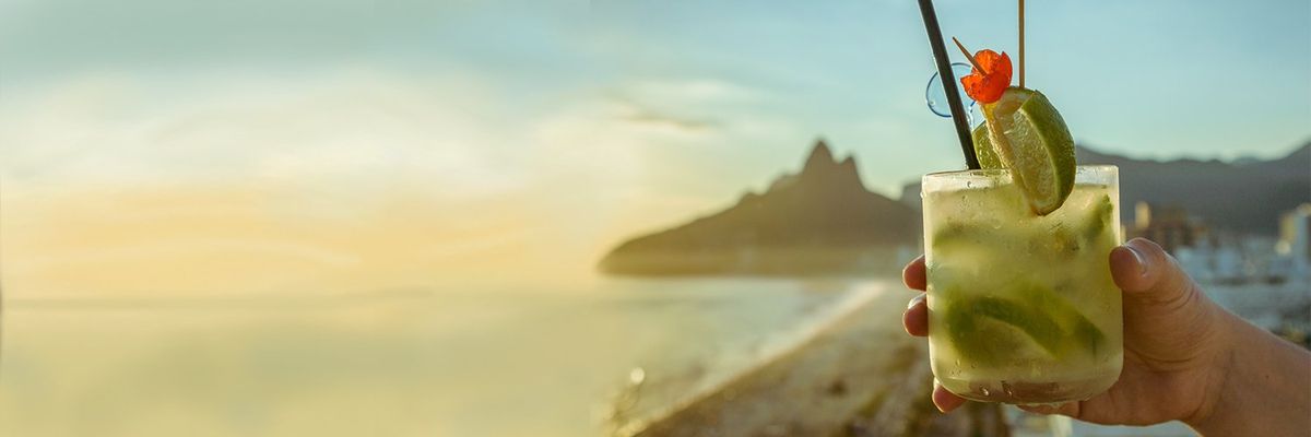 a person holding a caipirinha on the beach