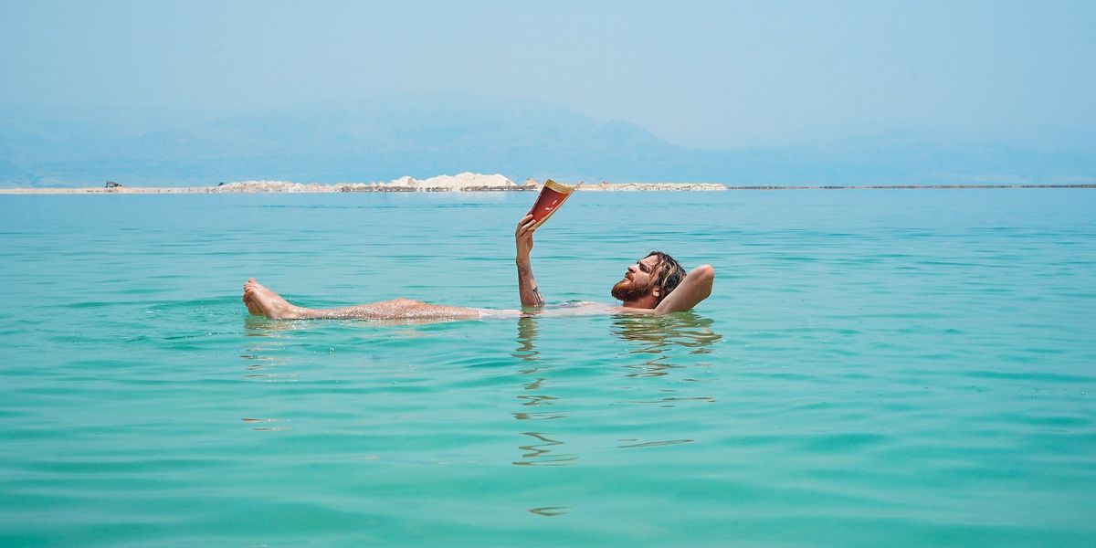 A man floats on his back in the ocean, while reading a book