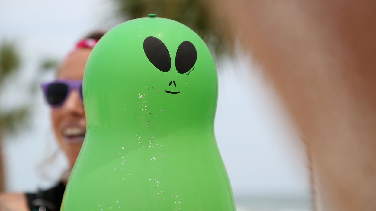 A green alien inflatable with glitter sprinkled on it.