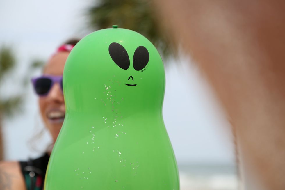 A green alien inflatable with glitter sprinkled on it.