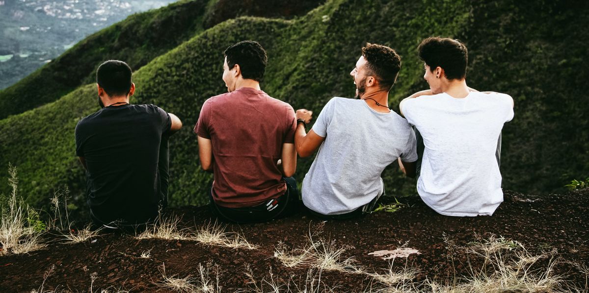 Four men sitting on a hill and laughing