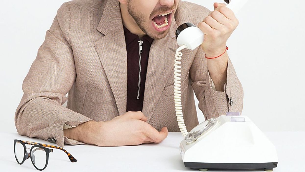 Man yelling into the receiver of a rotary phone