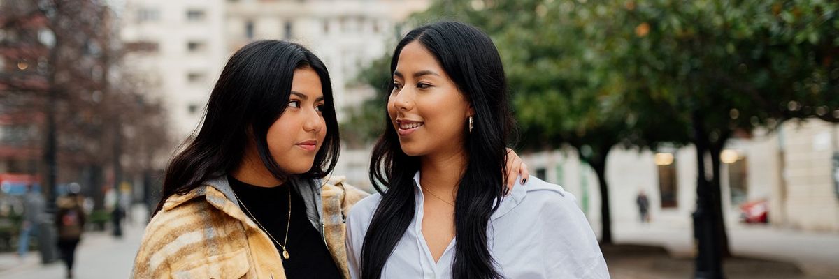two Latina women looking at each other and smiling