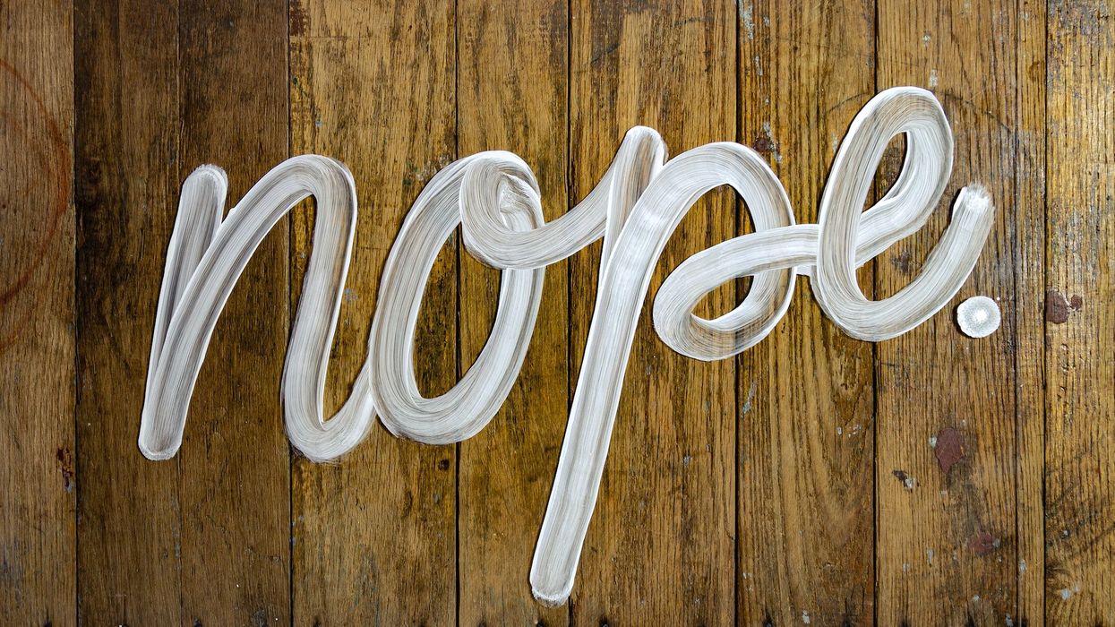 A sign saying "NOPE" written in white paint on a wooden wall